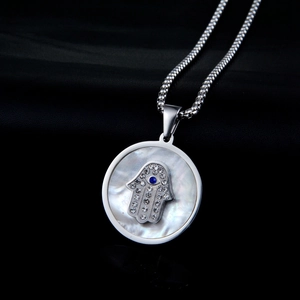 Macro shot of Hamsa Hand pendant with mother of pearl and blue evil eye stone