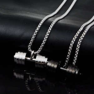 Detail of silver and black dumbbell pendants with sturdy box chains on leather background