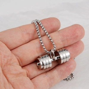 Detailed view of a silver dumbbell pendant held in hand on a bead chain necklace