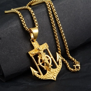 Detailed macro view of a gold anchor cross pendant featuring a fine crucifix and box chain