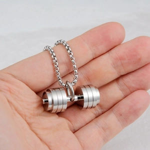 Macro shot of a hand holding a silver stainless steel dumbbell pendant on a box chain