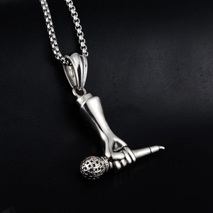 Détail d'un pendentif micro hip-hop argenté avec chaîne box sur cuir noir texturé