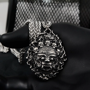 Macro detail of vintage silver lion mask pendant with intricate 3D relief carving