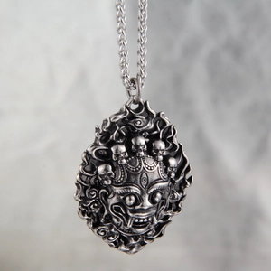 Close-up of vintage silver lion mask pendant with skull crown and intricate carving