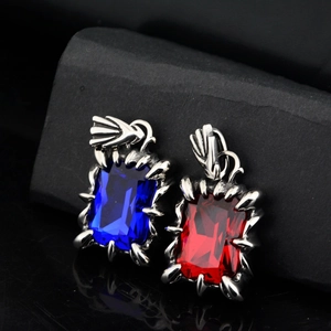 Détail des pendentifs griffe de dragon bleu saphir et rouge rubis sur roche sombre