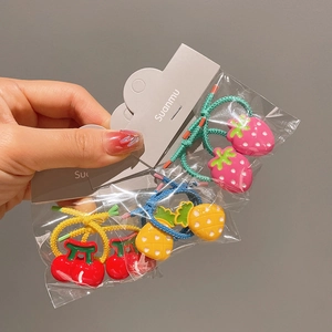 Detail of fruit-themed hair ties with strawberry and pineapple charms in packaging