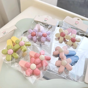 Close-up of 5 pairs of colorful macaron flower hair clips in a clear retail package