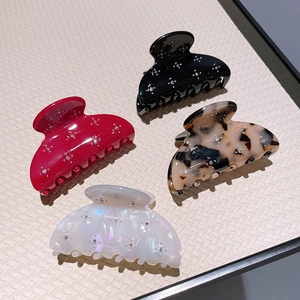 Detail of four acetate hair claws in black, wine red, tortoiseshell, and pearl white with rhinestones