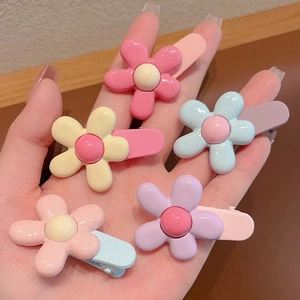 Detail showing macaron color flower hair clips in hand for size and texture reference