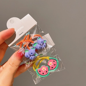 Close-up of cute fruit hair ties featuring blueberry and watermelon charms in packaging