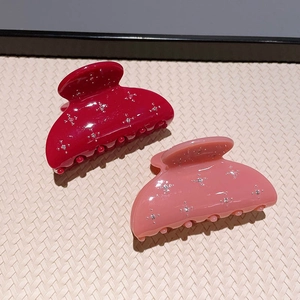 Close-up of sparkling star pattern on dark red and light pink acetate hair claws