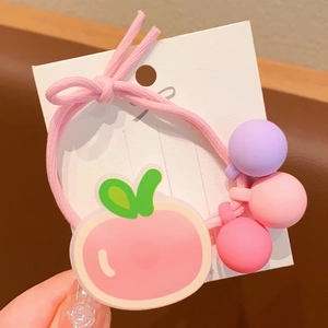 Détail de l'élastique à cheveux rose avec pendentif pêche et perles de macaron mat