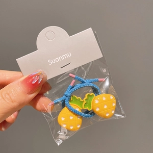 Detailed close-up of blue elastic hair tie with cute yellow pineapple charms in packaging