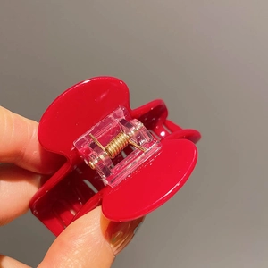 Detail view of red glossy hair claw clip showing durable gold metal spring mechanism