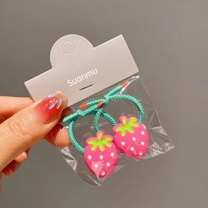 Close-up of pink strawberry charms on green elastic hair ties for girls