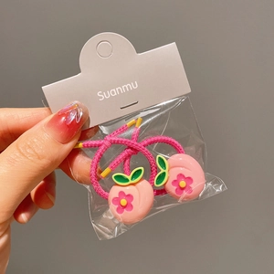Close-up of pink peach charm elastic hair ties for girls in detailed packaging