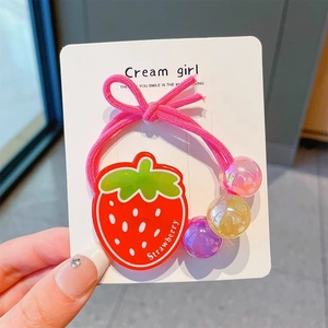 Gros plan d'un élastique à cheveux rose avec fraise en acrylique et perles colorées