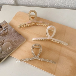 Detailed view of three acetate marble hair claws with elegant golden metal base