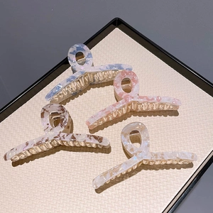 Summer acetate claw clips in four marble colors arranged on a textured display tray