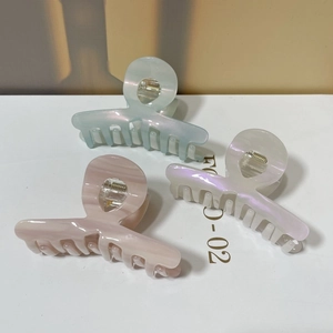 Three medium acetate shark hair clips in light green, lotus pink, and pearlescent white