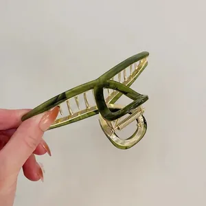 Close-up of a high-quality green acetate hair claw clip with a strong gold metal frame