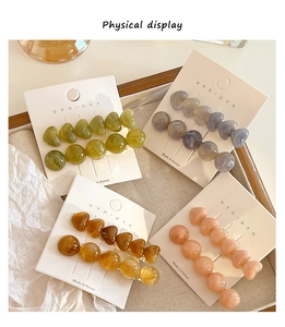 Detail of marble resin heart hair clips in green and amber on a display card