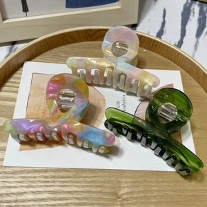 Detailed view of large marble texture hair claws and translucent green clips in a tray