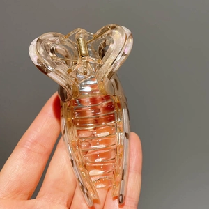 Detail of transparent large hair claw clip with beige marble edges and gold spring