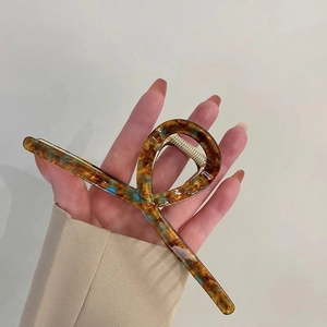 Close-up of tortoise shell pattern hair claw with amber and blue acetate texture detail