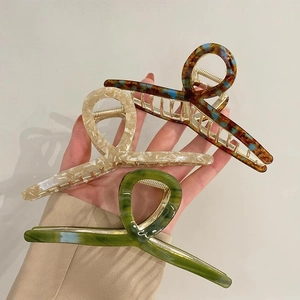 Three large acetate hair claws in marble and tortoiseshell patterns with gold springs
