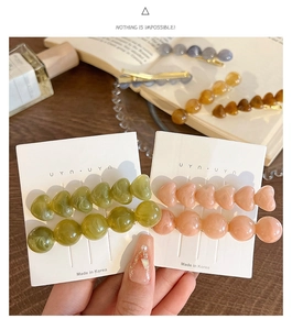 Detailed macro view of resin hair clips with marble texture on white paper cards