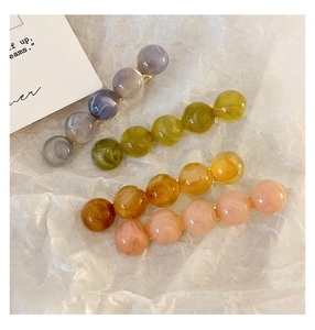Detail of four acrylic marble beads hair clips in grey, green, amber, and pink