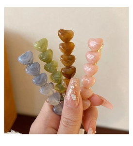 Detailed close-up of marble texture resin heart hairpins in four different colors