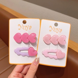 Dettaglio di fermagli per capelli in resina a forma di cuore rosa e viola su carta
