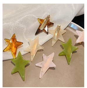 Detailed view of acetate star hair clips in amber and green on a stylish tray
