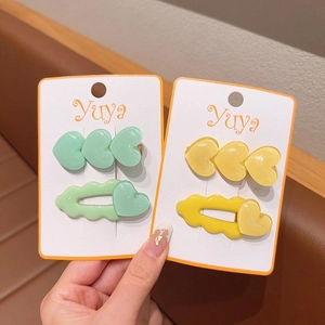 Dettaglio di fermagli per capelli a forma di cuore verde menta e giallo limone con glitter