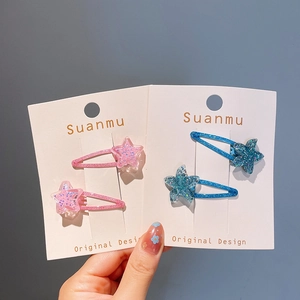 Détail de barrettes étoile à paillettes en rose et bleu sur carte d'affichage