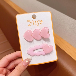 Dettaglio di fermagli per capelli rosa a cuore con glitter su cartoncino bianco