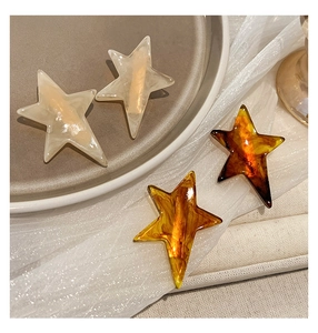 Detailed close-up of star hair clips in cream marble and amber tortoiseshell resin finishes