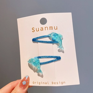 Détail de barrettes dauphin à paillettes bleues avec sequins sur carte de présentation