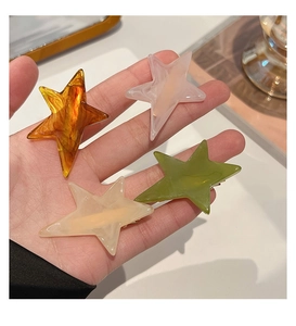 Close-up of hand holding colorful star-shaped acetate hair clips with marble texture