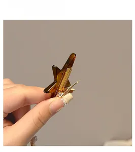 Close-up of star-shaped amber acrylic hair clip with gold metal alligator base