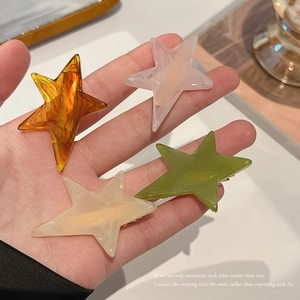 Star-shaped acetate hair clips in four elegant marble patterns held in hand