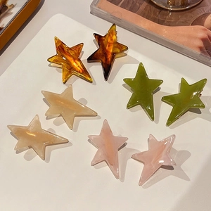 Colorful star-shaped acetate hair clips in amber, green, white, and pink finishes