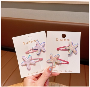 Detailed view of four glittery starfish hair clips in pink and blue on display cards