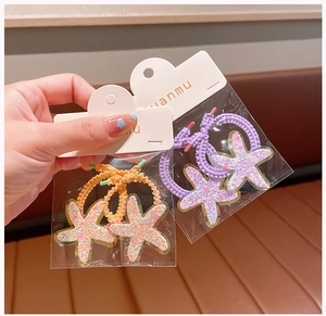 Detail of star-shaped hair ties in purple and orange with sequined acrylic finish