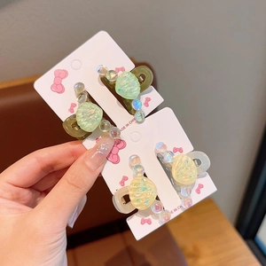 Détail des mini pinces à cheveux en forme de coquillage avec perles irisées et résine