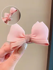 Detail view of pink double-layered bow hair clip showing secure metal crocodile clip grip