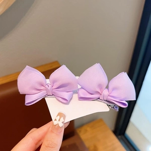 Detail view of double-layered purple satin bow hair clips on white display card
