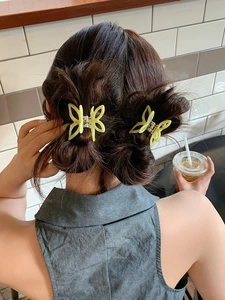 Close-up of elegant light yellow butterfly hair clips with delicate hollow design